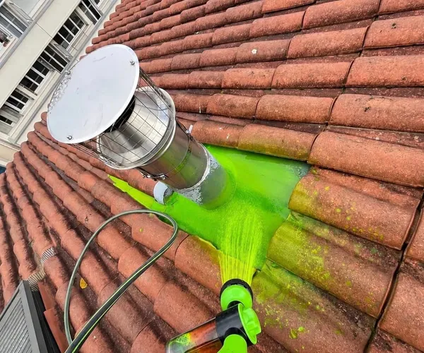 Test d’aspersion avec eau colorée verte sur une toiture en tuiles autour d’une sortie métallique