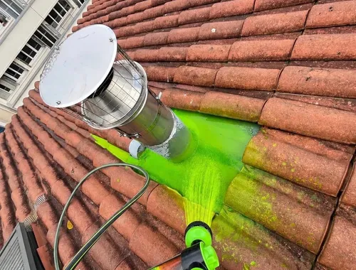Test d’aspersion avec eau colorée verte sur une toiture en tuiles autour d’une sortie métallique