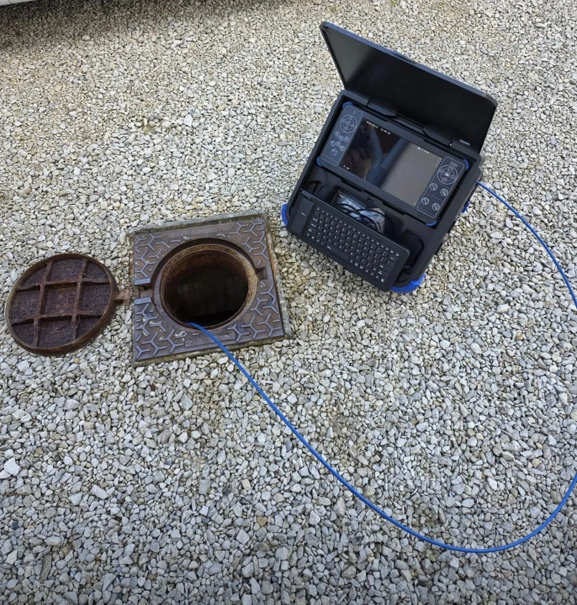Caméra d’inspection à tête rotative installée près d’un regard ouvert sur du gravier