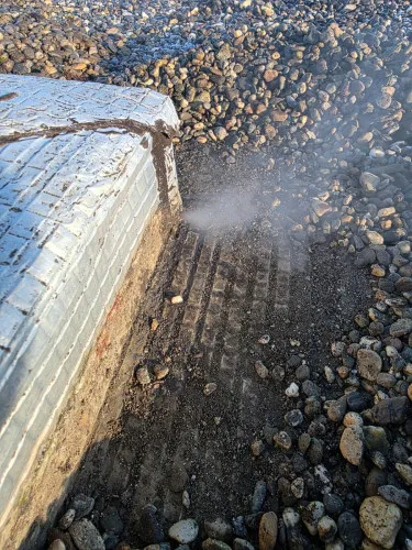 Panache de fumée au pied d’une structure en béton sur une toiture gravillonnée