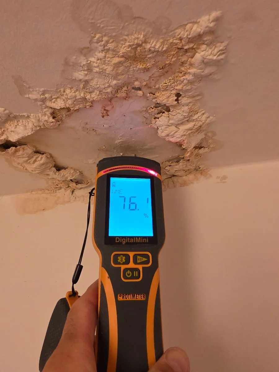 Humidimètre affichant 76,1 % sous un plafond fortement dégradé par l’humidité
