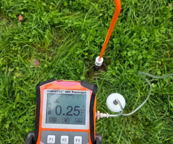 Détecteur de gaz traceur Sewerin relié à une sonde sur une pelouse