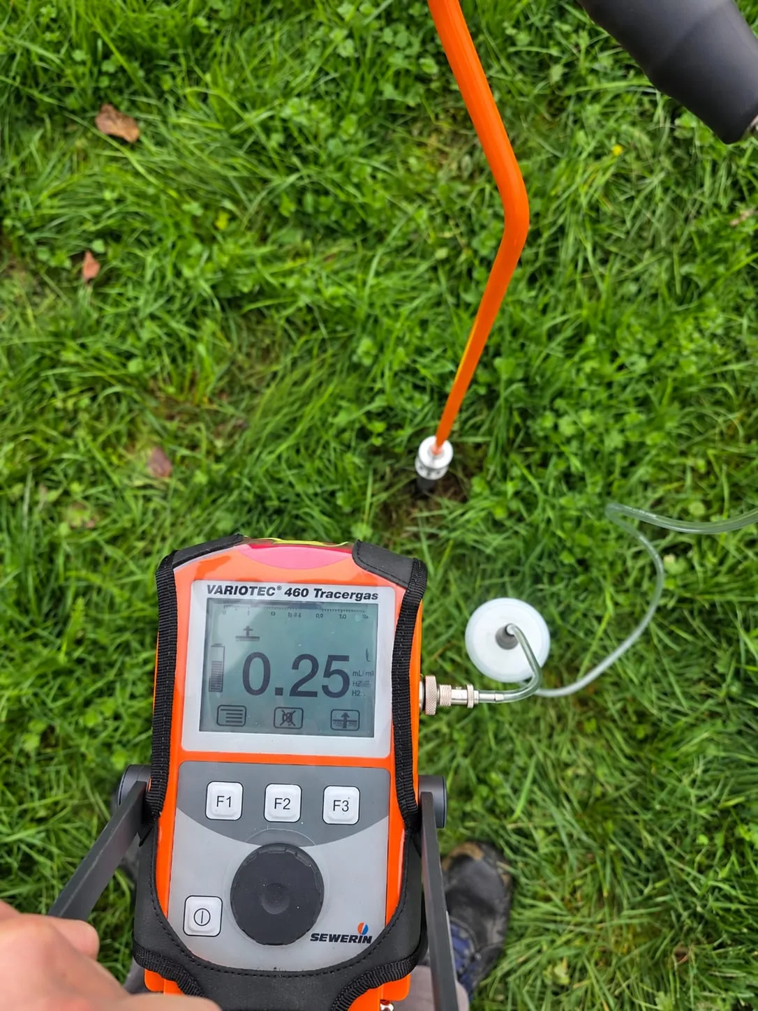 Détecteur de gaz traceur Sewerin relié à une sonde sur une pelouse
