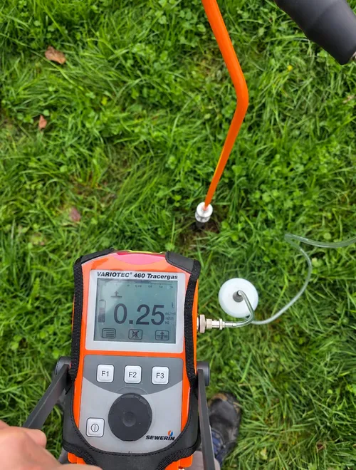 Détecteur de gaz traceur Sewerin relié à une sonde sur une pelouse